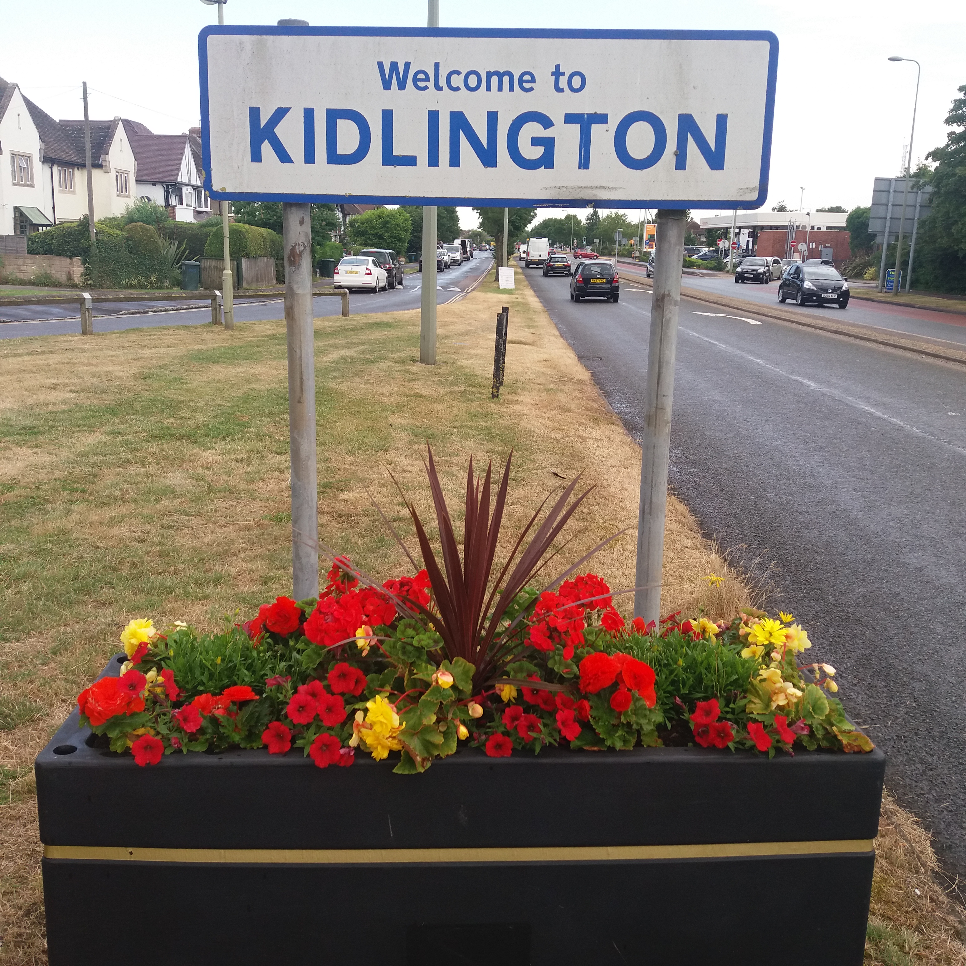 welcome to kidlington sign with flower baskets underneath